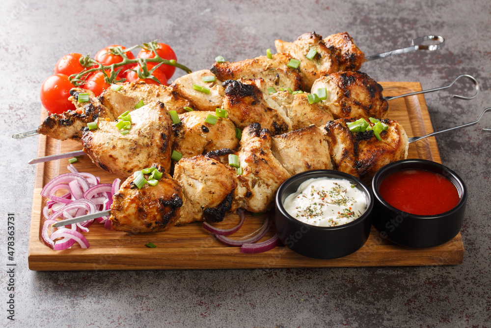 Grilled chicken shish kebab or shashlik on skewers closeup on wooden board close-up. Horizontal Grilled chicken shish kebab or shashlik on skewers closeup on wooden board close-up. Horizontal