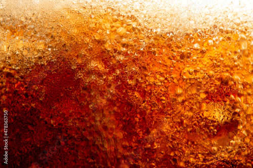 Close up view of the ice cubes in dark cola background. Texture of cooling sweet summer s drink with foam and macro bubbles on the glass wall. Fizzing or floating up to top of surface
