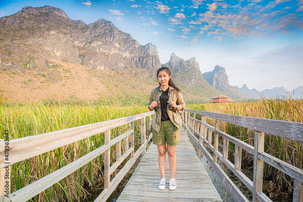 Freedom traveler woman standing with raised arms and enjoying a beautiful nature and cheering young woman backpacker at sunrise seaside mountain peak 