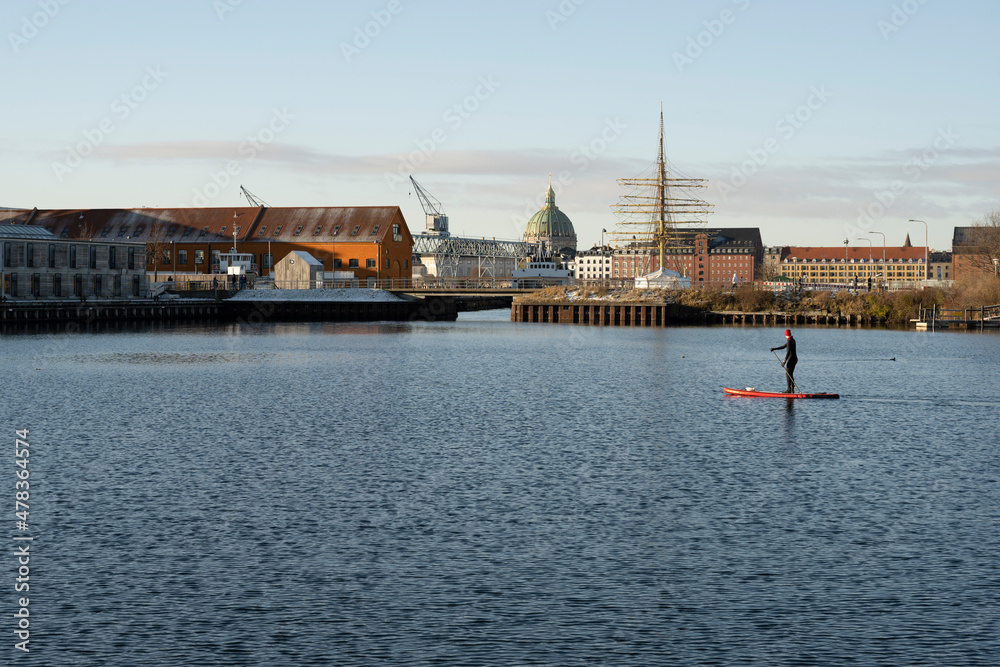 A man is engaged in water sports against the backdrop of a Danish cityscape