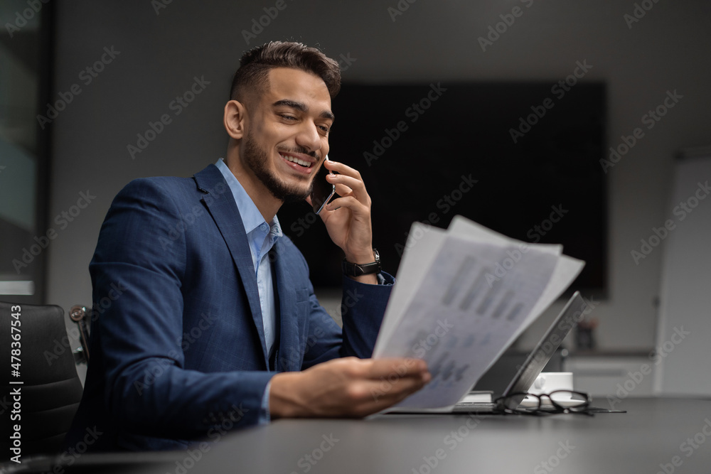 Happy arab CEO reading documents and having phone conversation Happy arab CEO reading documents and having phone conversation