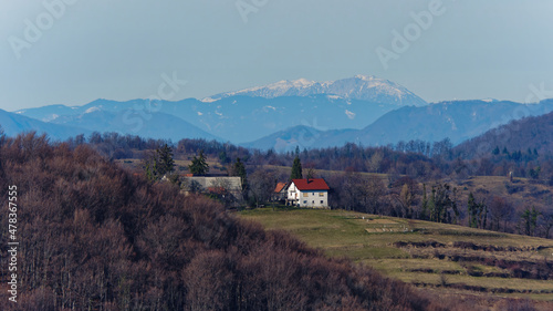 Picture of a sunny house with a red roof on a hill with mountains and sky in the background, Samobor, Croatia