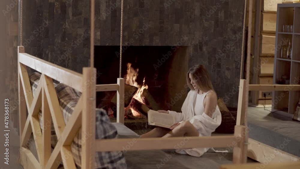 Relaxing near fireplace and reading the book Relaxing near fireplace and reading the book