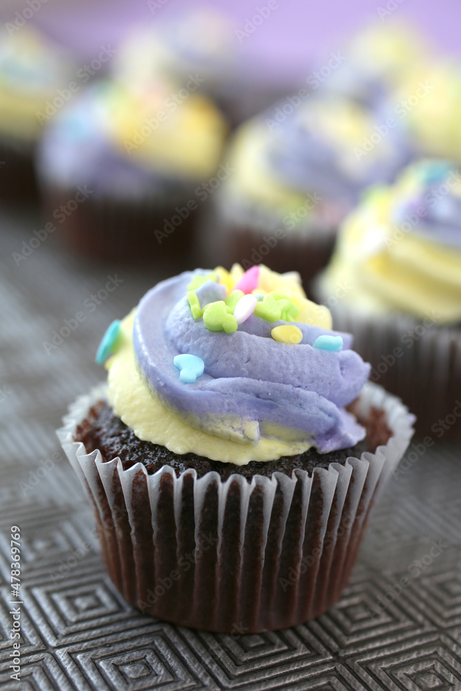 Top view of yellow and purple easter cupcake on lined background