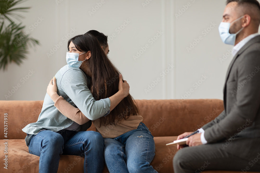 Happy couple in masks hugging reconciling at therapy session Happy couple in masks hugging reconciling at therapy session