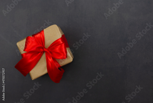 Gift box with red bow on a black background. Festive background. Copy space.