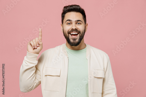 Young smiling happy caucasian man 20s wearing trendy jacket shirt holding index finger up with great new idea isolated on plain pastel light pink background studio portrait. People lifestyle concept. photo