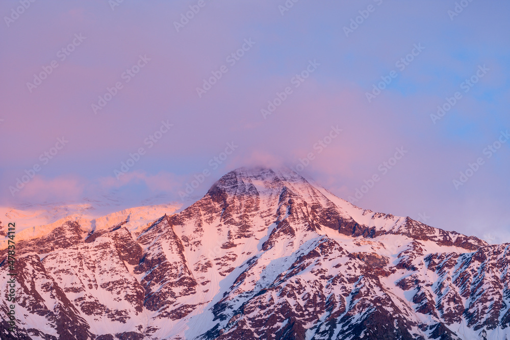 Mont Blanc and the Aiguille du Gouter surrounded by pink clouds in Europe, France, the Alps, towards Chamonix, in summer.
