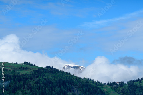 Clouds surround Mont Joly and Col de Voza and their forest in the Mont Blanc massif in Europe, France, the Alps, towards Chamonix, in summer, on a sunny day. photo