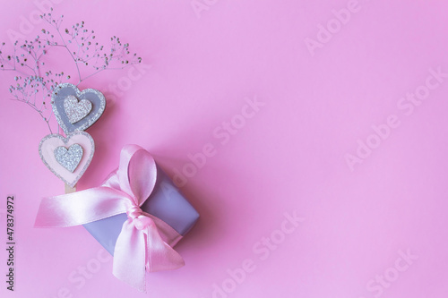 gift box with bow on pink background with hearts. Flat lay, top view, copy space.