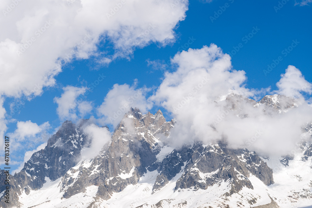 The Aiguille de Blaitiere and the Aiguille du Plan surrounded by clouds in the Mont Blanc massif in Europe, France, the Alps, towards Chamonix, in summer, on a sunny day.