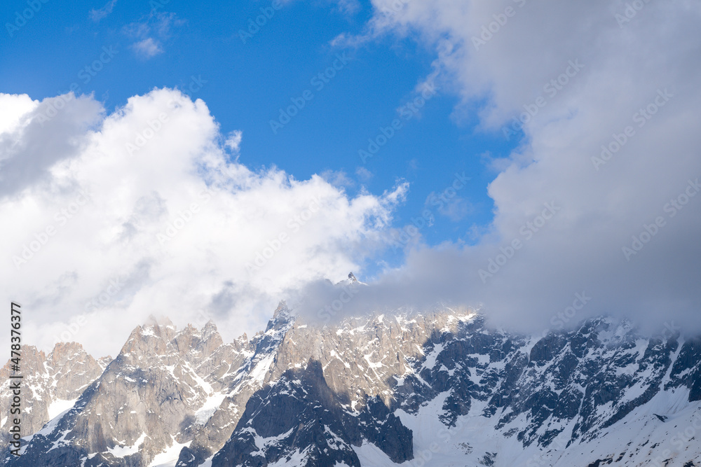 Clouds surround the Aiguille de Blaitiere and the Aiguille du Plan in the Mont Blanc massif in Europe, France, the Alps, towards Chamonix, in summer, on a sunny day.