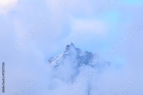 The Aiguille du Midi in the fog in the Mont Blanc massif in Europe, France, the Alps, towards Chamonix, in summer on a sunny day.