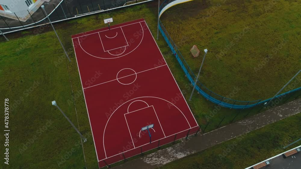 Contemporary bright red basketball ground with new marking near rink on