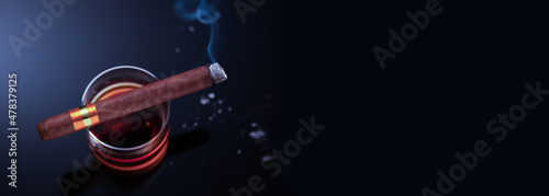 Brennende Zigarre liegt auf einem Glas mit Whiskey und raucht, Perspektive von oben photo