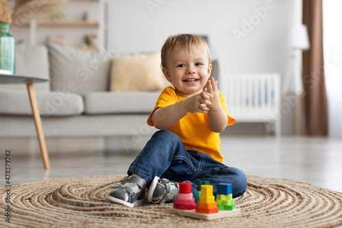 Fototapete Adorable toddler boy playing with educational wooden toy at home, clapping hands