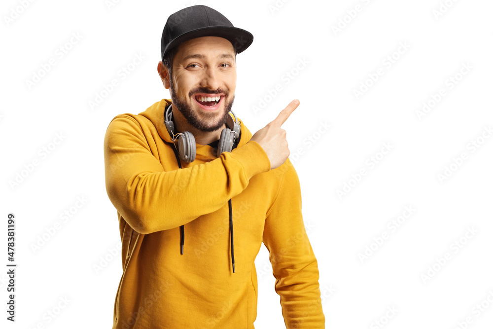 Cheerful guy with headphones and a cap pointing to the side Cheerful guy with headphones and a cap pointing to the side