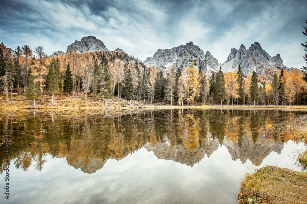 Autumnal panorama of Dolomite peaks and colored woods reflecting on lake waters. Lake Antorno, with the Cadini di Misurina in the background, Dolomites, Italy