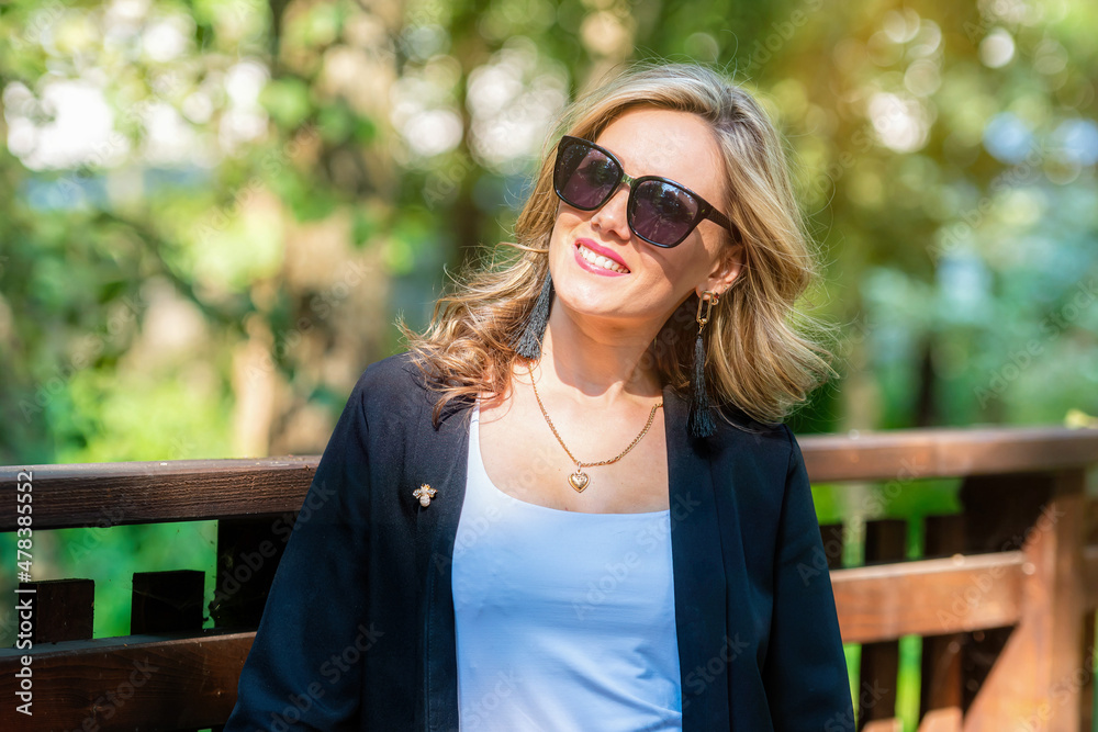 fashion portrait of a stylish nice blonde female in sunglasses on a defocused park background fashion portrait of a stylish nice blonde female in sunglasses on a defocused park background