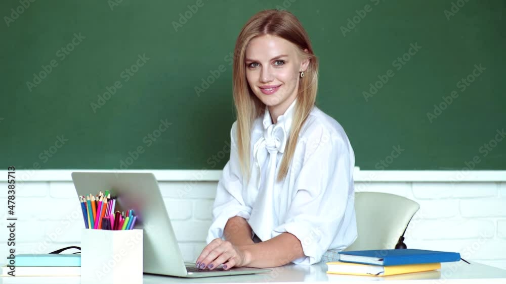 Teacher sitting at table and writing on notebook. Student working on a laptop, preparing for an exam. Educational process. Portrait of an college studenti in college. Teacher sitting at table and writing on notebook. Student working on a laptop, preparing for an exam. Educational process. Portrait of an college studenti in college.