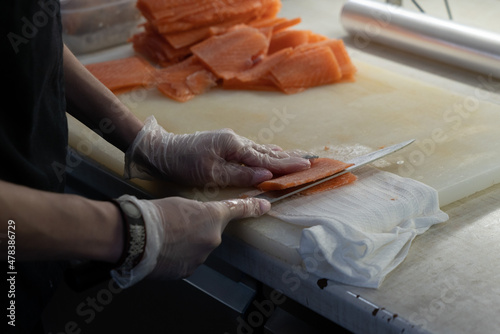 Photo of male hands in gloves which cuts a red fish on a board. Seafood and food