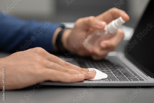 Hand of man with sanitizer for cleaning gadgets while pandemic