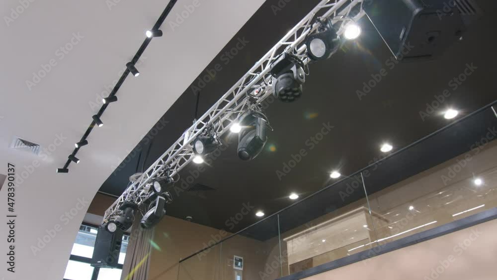 Metal beam with spotlights hangs from white ceiling illuminating hallway of contemporary building low angle shot