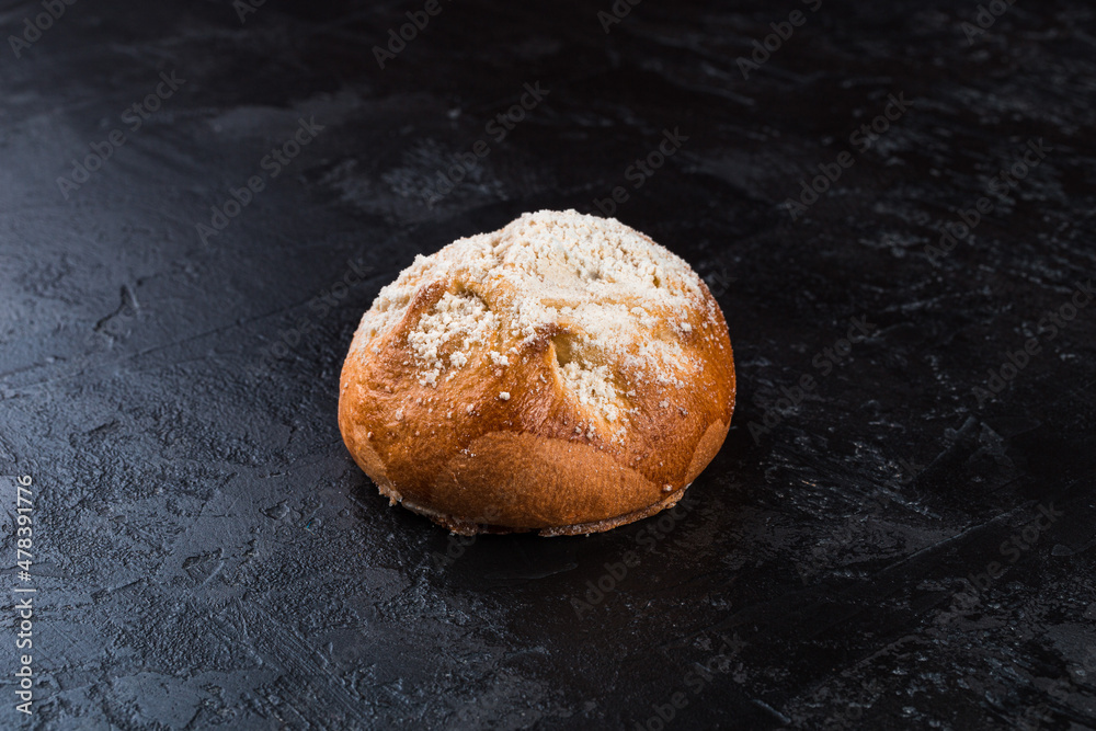Freshly baked tasty bun on a dark table. Tasty baked goods straight from the bakery. Black background.