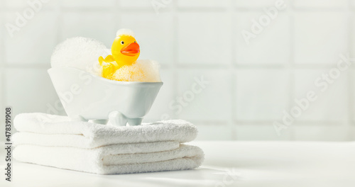 Fototapete A miniature bubble bath, yellow rubber duck and white towels on bathroom counter