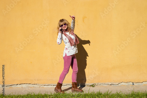 woman with mobile phone isolated on the wall outdoors © carballo