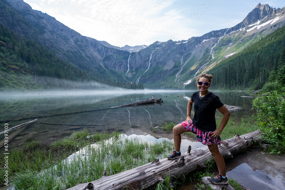 Adult woman hiker smiles and poses at Avalanche Lake in Glacier National Park Adult woman hiker smiles and poses at Avalanche Lake in Glacier National Park