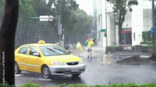 Blurred defocused Extreme Wind And Rain During A Super Typhoon Megi, Asian people cross road, used a yellow oilskin and umbrella in crosswalk on street Taipei. Strong hurricane photo