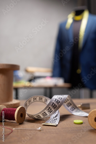 Thread spool and needle with sewing tools on table. Concept of clothes atelier workplace