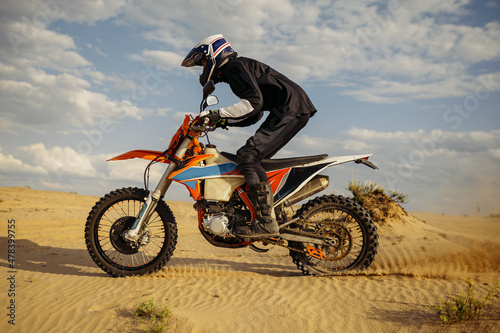 Professional motocross rider driving on sand dune
