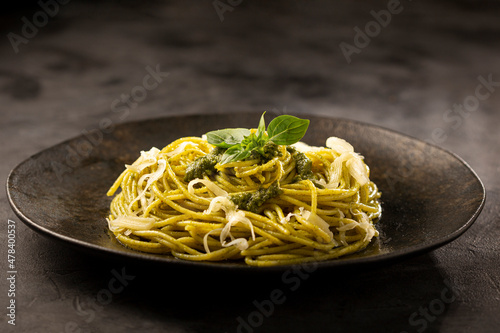 Pasta spaghetti with pesto sauce and basil leaf.