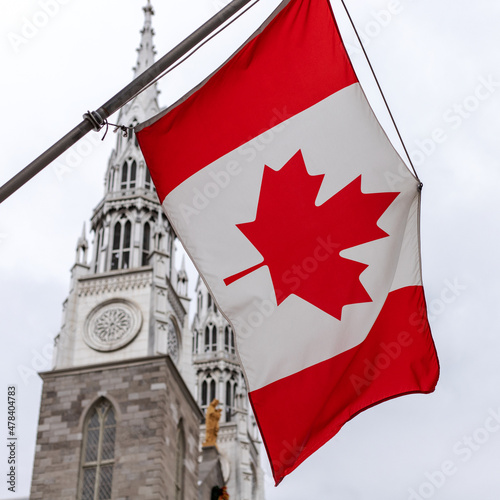 Close up of Canadian flag in front of the Notre-Dame Cathedral Basilica in Ottawa, Canada against sky