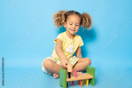 Cute kid playing with color toy over blue background