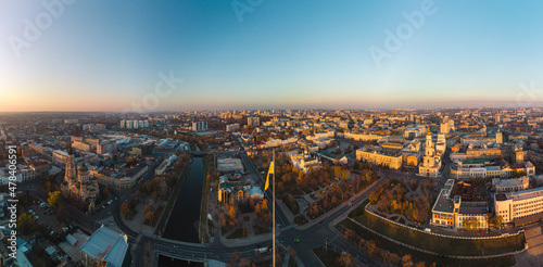 Flagpole with flag of Ukraine with clear autumn cityscape, city streets. Wide panoramic aerial view above river Lopan embankment near Annunciation Cathedral in Kharkiv, Ukraine photo