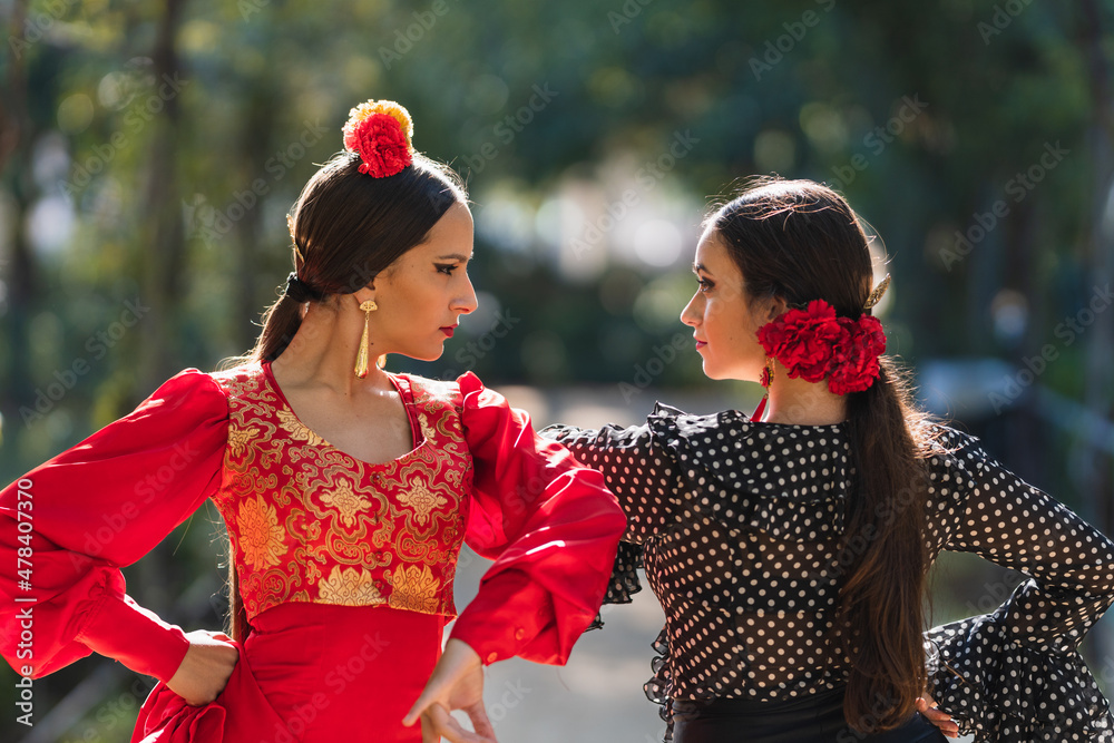 Obraz premium Two women in flamenco traditional costume dancing side by side outdoors