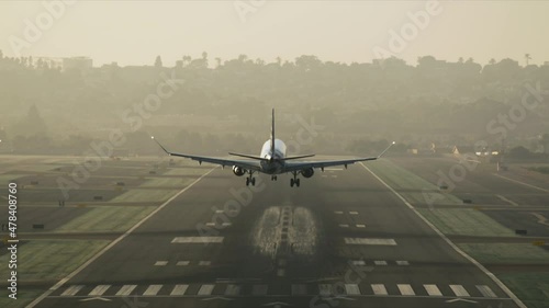 Big commercial plane serving domestic flight as seen from above. Huge aircraft landing on a runway with a cityscape behind. High quality 4k footage