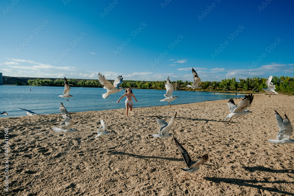 Teen girl running on beach chasing seagulls Stock Photo | Adobe Stock