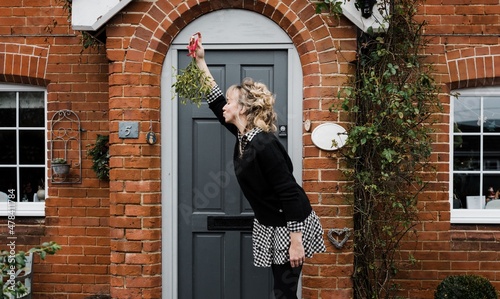 woman holding mistletoe leaning forward for a kiss photo