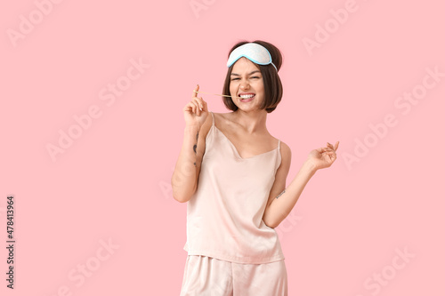 Emotional young woman in pajamas and with chewing gum on color background