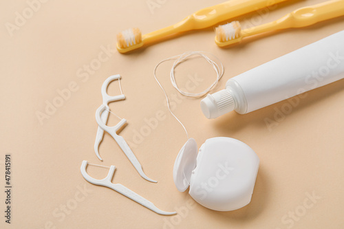 Dental floss, toothpicks, brushes and paste on beige background