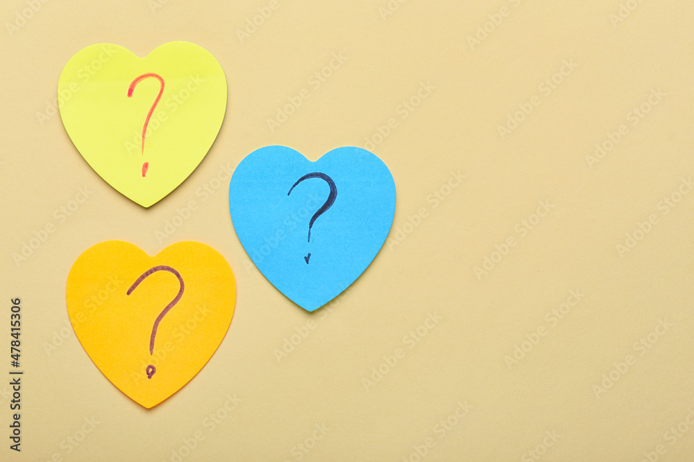 Heart shaped sticky notes with question marks on beige background Heart shaped sticky notes with question marks on beige background