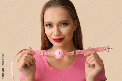 Young woman with mouth gag on light background