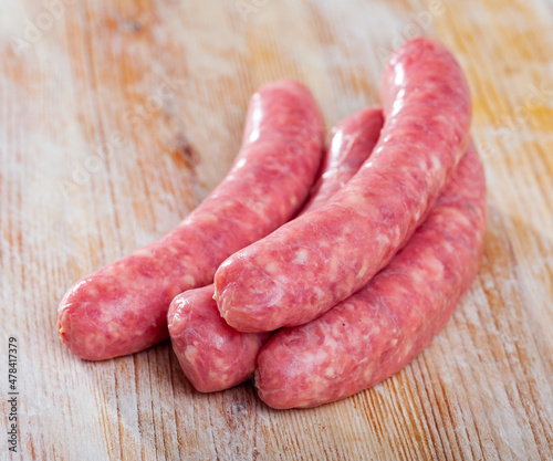 Raw sausages for frying on wooden surface at home kitchen