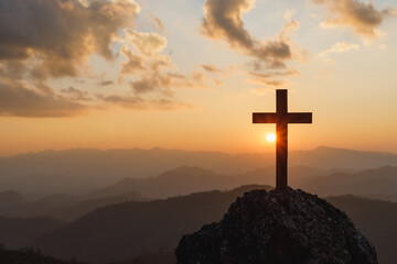 Silhouettes of crucifix symbol on top mountain with bright sunbeam on the colorful sky background