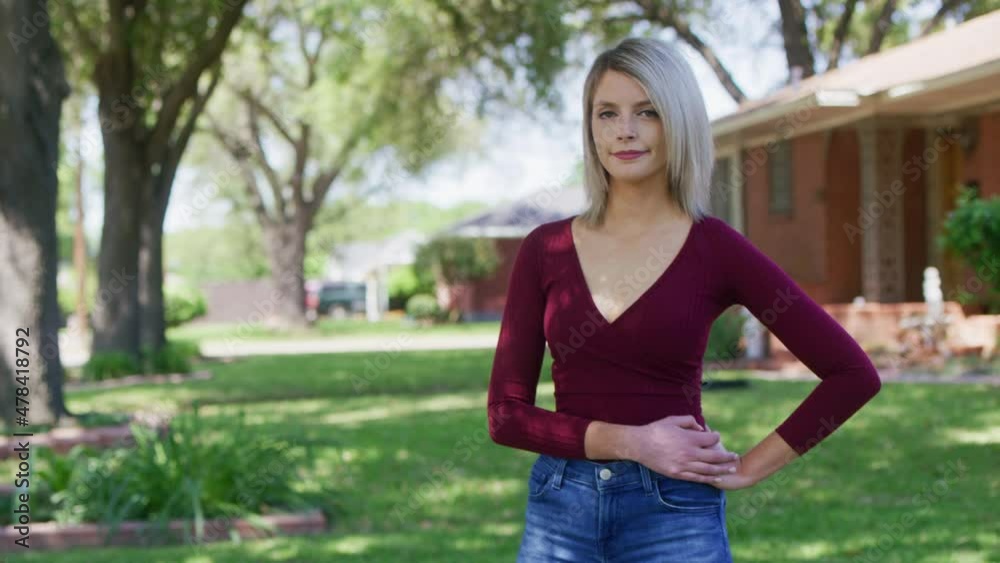Hipster woman looks at the camera while holding her waist in front of a house Hipster woman looks at the camera while holding her waist in front of a house