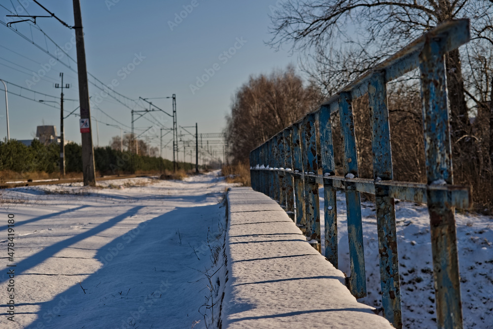 Mostek kolejowy z barierką niebieską w śniegu zimową porą .